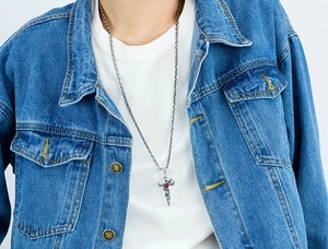 Close-up of a vintage gothic sword cross necklace with a red heart and silver wings