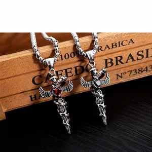 Macro shot of two vintage sword pendants with red and black heart gems on wood