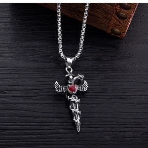 Gothic silver sword pendant with red heart gem and coiled snake on vintage wood background