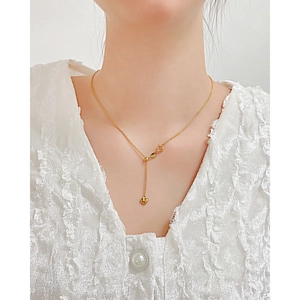 Detalle del collar con colgante de corazón dorado en modelo con encaje blanco y cadena