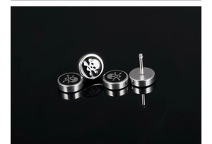 Makro-Detail der Punk-Totenkopf-Ohrringe mit schwarzem Emaille und silbernem Titanstahl