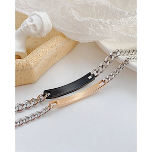 Gros plan de bracelets de couple en acier titane avec plaques gravées noires et or rose