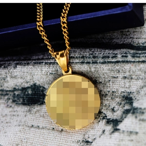 Gros plan sur la chaîne corde dorée et le pendentif rond poli sur tissu texturé