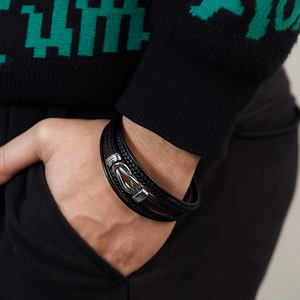Detail of multi-layer woven leather bracelet with silver metal knot clasp and red stitching