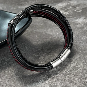 Macro detail of men's layered leather bracelet with red stitching and silver magnetic clasp