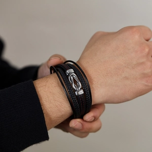 Macro detail of men's multi-layer braided black leather bracelet with silver metal clasp