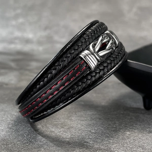 Detail of multi-layer black leather bracelet featuring distinct red stitching and metal clasp