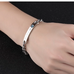 Detail of silver Cuban chain bracelet with Her King engraving and blue zircon on hand