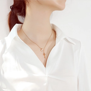 Detail of rose gold heart lock and key pendant necklace worn on a female model neck