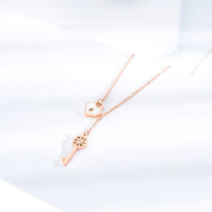 Rose gold heart lock and key pendant necklace on elegant white fabric background