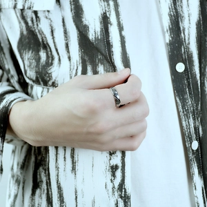 Close-up of a minimalist silver heart ring with subtle engravings on a model's finger