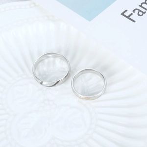 Close-up of minimalist couple rings with heart pattern on a textured ceramic dish