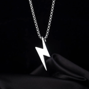 Collar con colgante de rayo en plata pulida sobre elegante fondo de seda negra