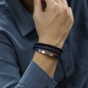 Détail d'un ensemble de bracelets en cuir bleu et perles pour homme porté par un mannequin