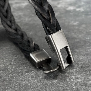 Macro view of hand-woven black leather bracelet with retro metal clasp detail