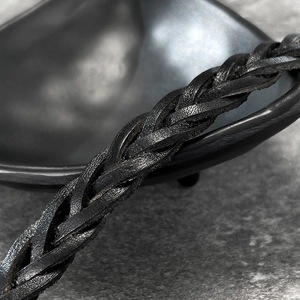 Macro view of hand-woven black leather bracelet with textured spiral weaving detail