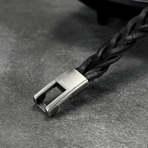 Close-up of black braided leather bracelet featuring a polished silver metal clasp