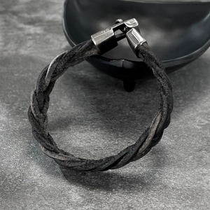 Handmade braided leather bracelet for men with vintage silver metal clasp on dark surface