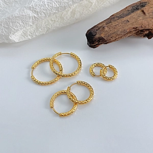 Three sizes of gold round hoop earrings with detailed hammered metal texture in macro view