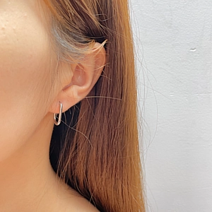 Close-up of polished silver oval geometric hoop earrings worn for a minimalist look