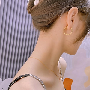 Detailed close-up of textured gold hoop earrings and a pearl necklace worn by a model
