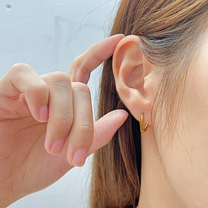 Close-up of a minimalist polished gold geometric hoop earring worn by a model