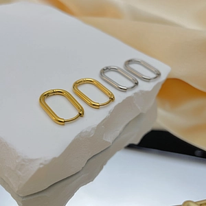 Polished gold and silver geometric rectangular U-shaped earrings on marble display