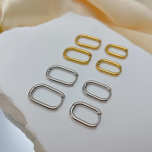 Detailed macro of gold and silver geometric hoop earrings on a marble display surface