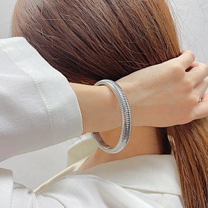 Detailed view of silver titanium steel bangle with ribbed texture on woman wrist