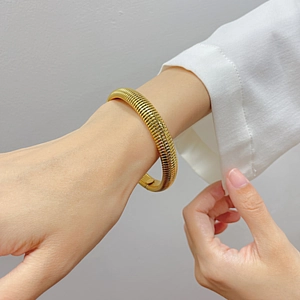 Detailed view of golden Tubogas spiral bracelet with textured finish on model wrist