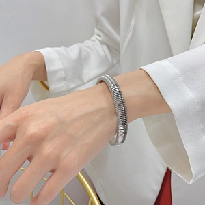 Minimalist silver wire-wrapped spring bracelet in polished stainless steel for women