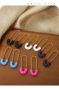 Macro detail of pin-style U-shaped earrings in five enamel colors on silk fabric