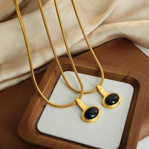 Collier chic en acier titane doré avec pendentif ovale en pierre noire sur fond de soie