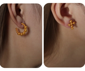 Vista detallada de pendientes de aro con cuentas y aretes de cruz bañados en oro