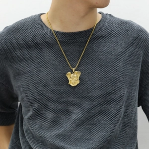 Dettaglio ravvicinato di una collana da uomo con ciondolo a teschio dorato indossata
