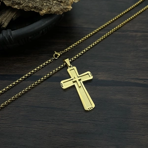Detail of a dual-layered golden cross pendant with box chain on dark wood background