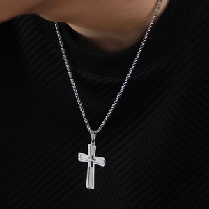 Close-up of a silver double-layered cross pendant with matte and polished steel finishes