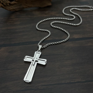 Detail of silver double-layered cross pendant with pearl chain on dark wood background