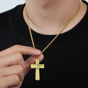 Close-up of gold double-layer cross pendant on box chain worn by male model