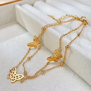 Detail eines minimalistischen Gold-Schmetterlings-Doppelstrang-Fußkettchens mit Perlen