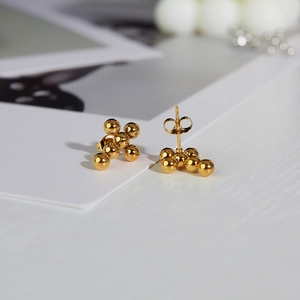 Close-up of golden cluster stud earrings with polished spherical beads and butterfly backs