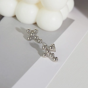 Macro detail of silver cross earrings made of smooth metal spheres with reflective finish