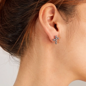 Detail of silver cross stud earring made with polished beads on female ear