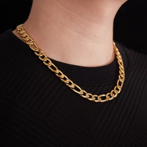 Détail d'une chaîne Figaro dorée portée sur un haut en maille noire pour homme