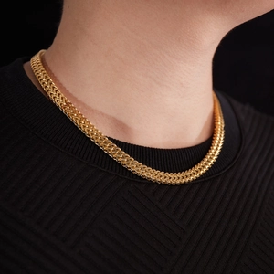 Close-up of a golden Franco link chain necklace worn on a black textured sweater