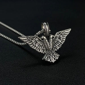 Détail macro du pendentif aigle à deux têtes argenté antique avec plumes en relief