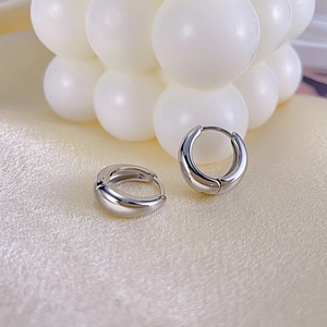 Détail des boucles d'oreilles créoles argentées avec une finition polie miroir