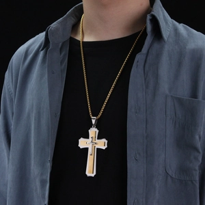 Detail van een drielaagse goud en zilveren kruisbedel met een gouden kogelketting
