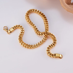 Macro detail of golden Cuban link chain featuring a lobster clasp and polished finish