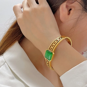 Detail of vintage gold bracelet with green rectangular stone worn by a model